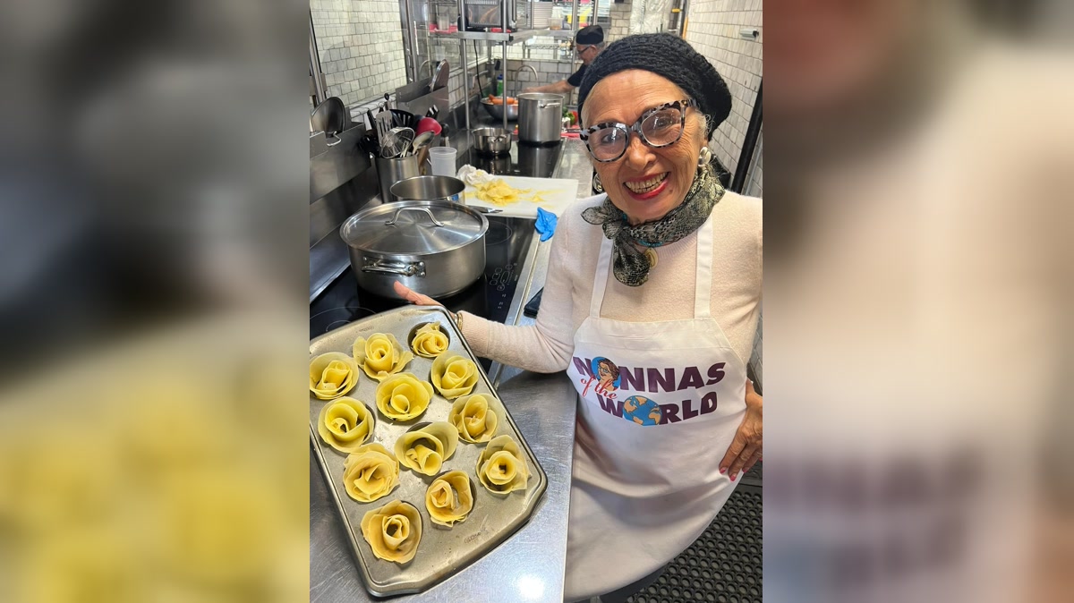 Một nonna mỉm cười bên khay pasta tạo hình hoa trong căn bếp Enoteca Maria