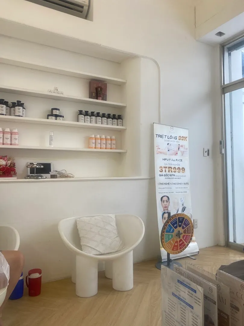 Không gian spa với kệ sản phẩm chăm sóc da, ghế ngồi và bảng giới thiệu dịch vụ.