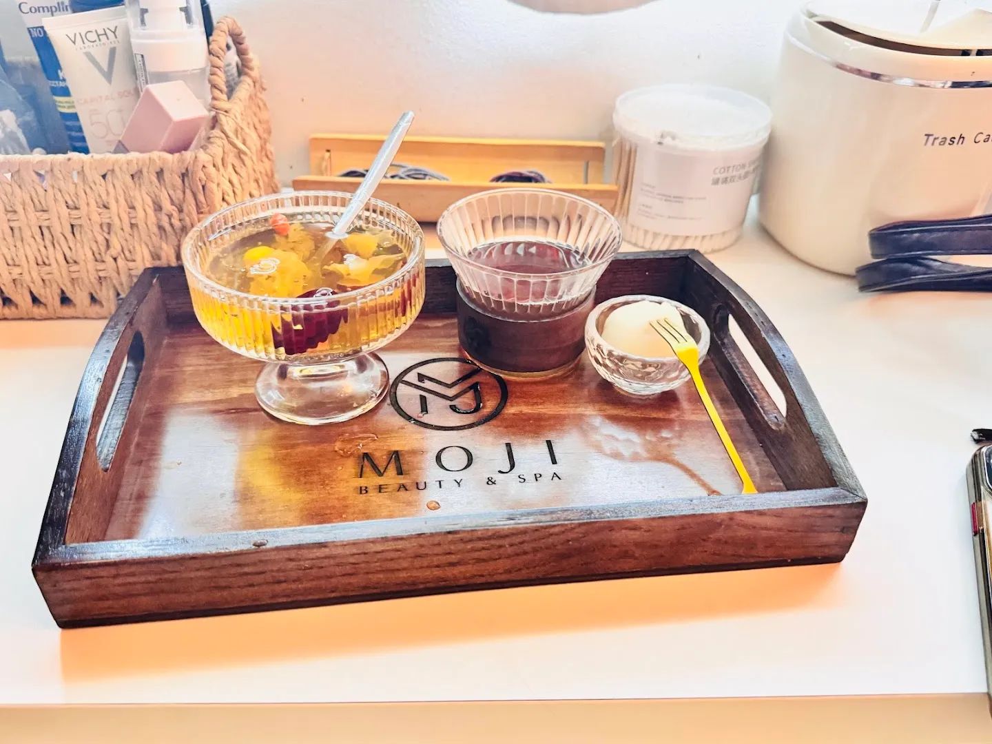 Khay phục vụ đồ uống và món tráng miệng mang logo MOJI Beauty & Spa.