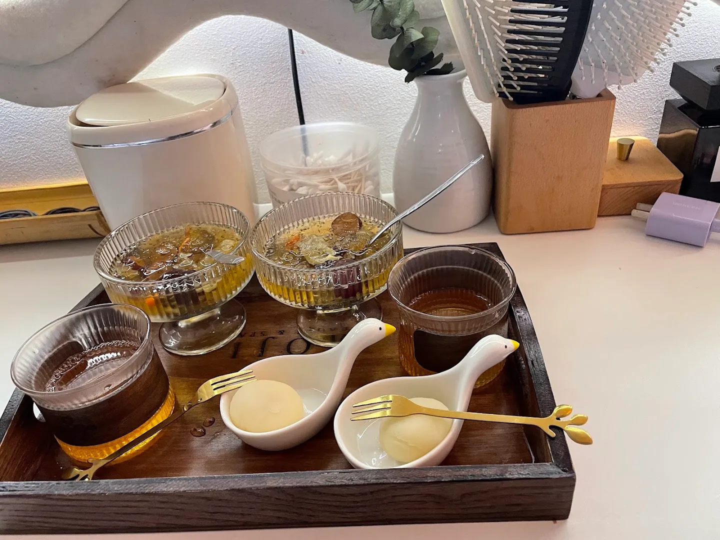 Khăn ấm, cốc nước thảo mộc và các vật dụng chăm sóc được chuẩn bị trên khay.