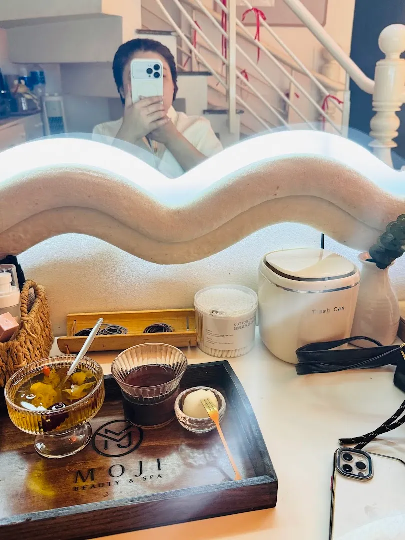Bộ dụng cụ chăm sóc và khay đồ uống mang logo MOJI SPA trên bàn spa.
