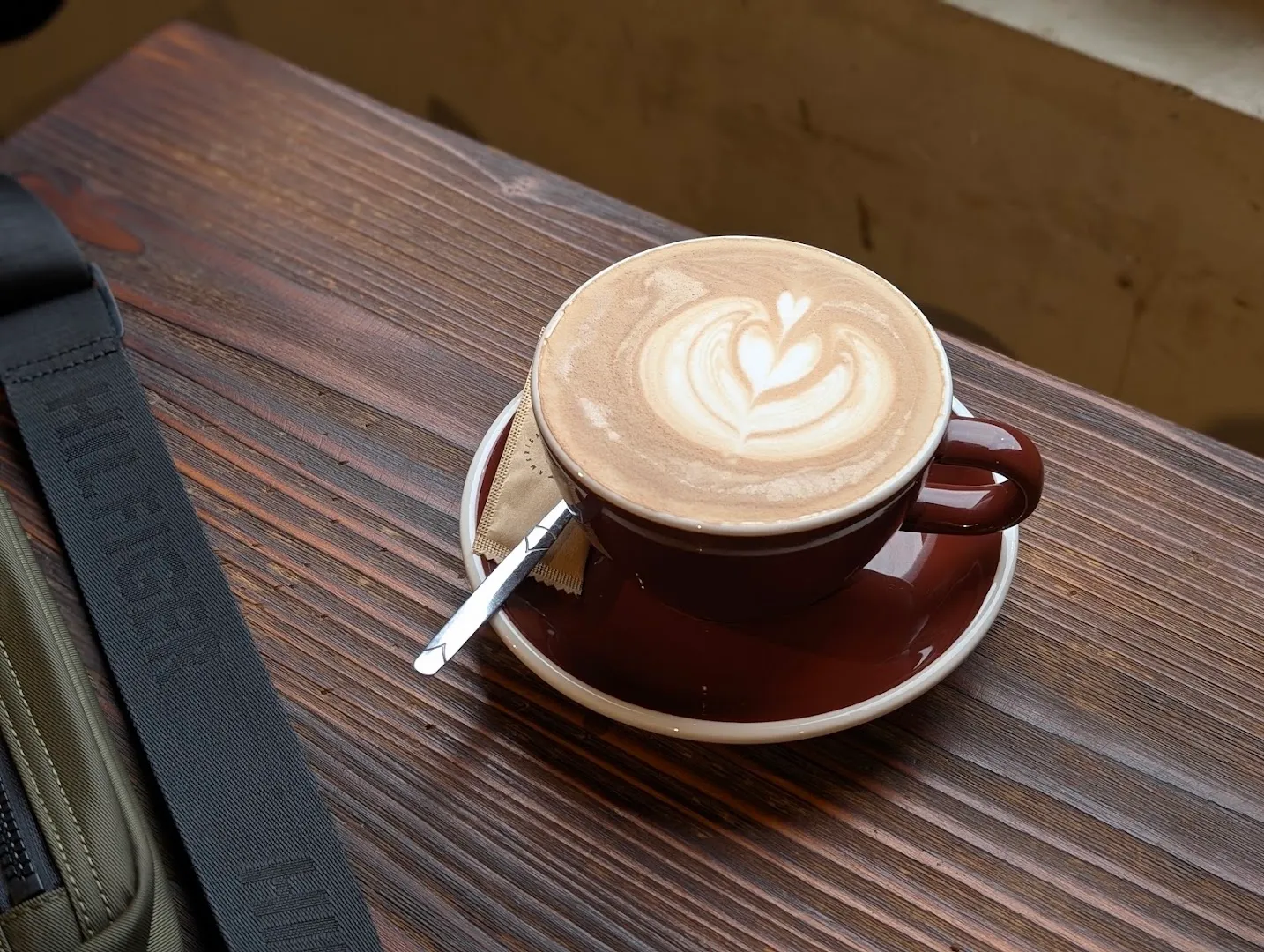 Tách cà phê sữa với hình latte art trên bàn gỗ