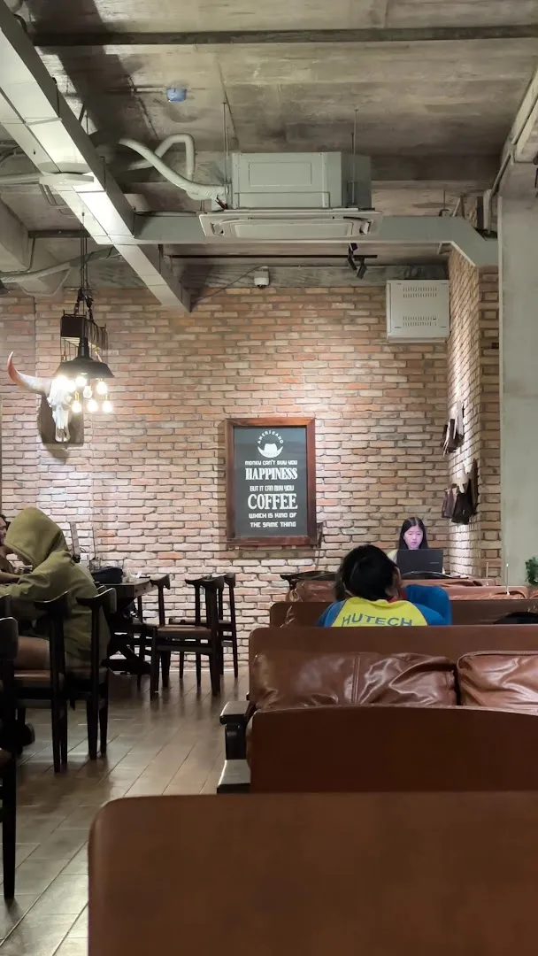 Không gian bên trong quán với tường gạch, bàn ghế và khu vực ghế sofa.