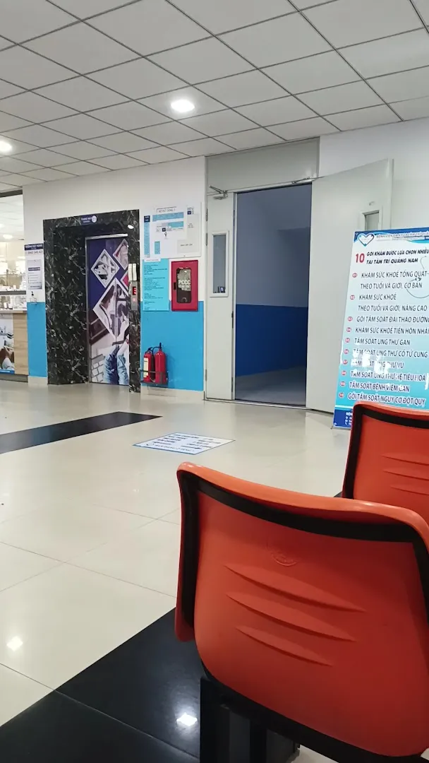 Khu vực sảnh chờ với ghế ngồi, cửa phòng và bảng thông tin y tế.