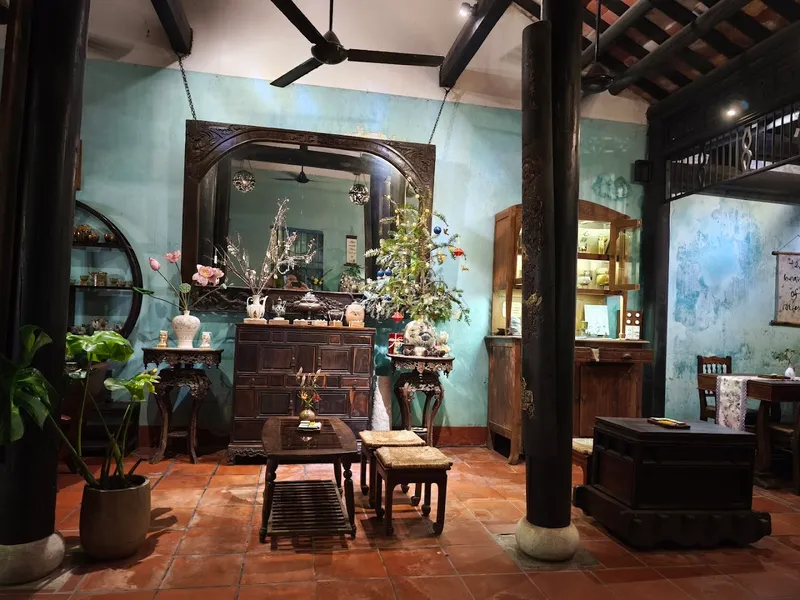Không gian phòng trà mang phong cách truyền thống với nội thất gỗ chạm khắc, bàn ghế thấp và đồ trang trí nghệ thuật.