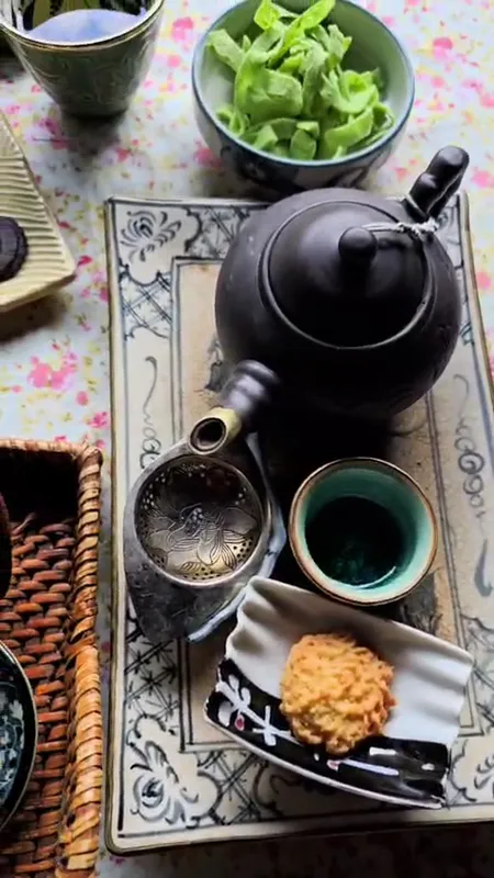 Bộ ấm trà đen cùng chén trà và bánh ăn kèm trên khay.