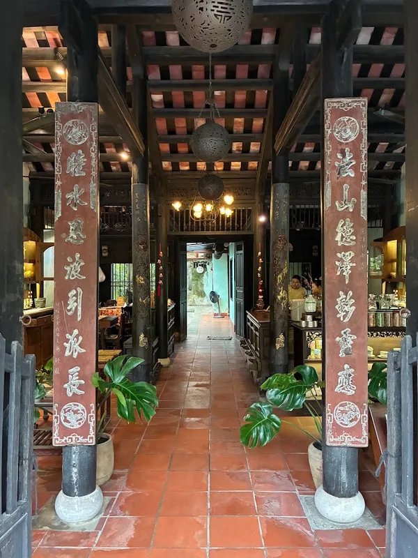 Không gian nội thất đậm nét truyền thống với cột gỗ, đèn lồng và lối vào lát gạch.