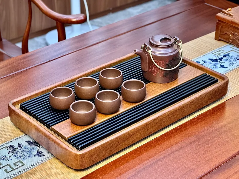 Bộ ấm chén trà bằng gốm trên khay trà gỗ.