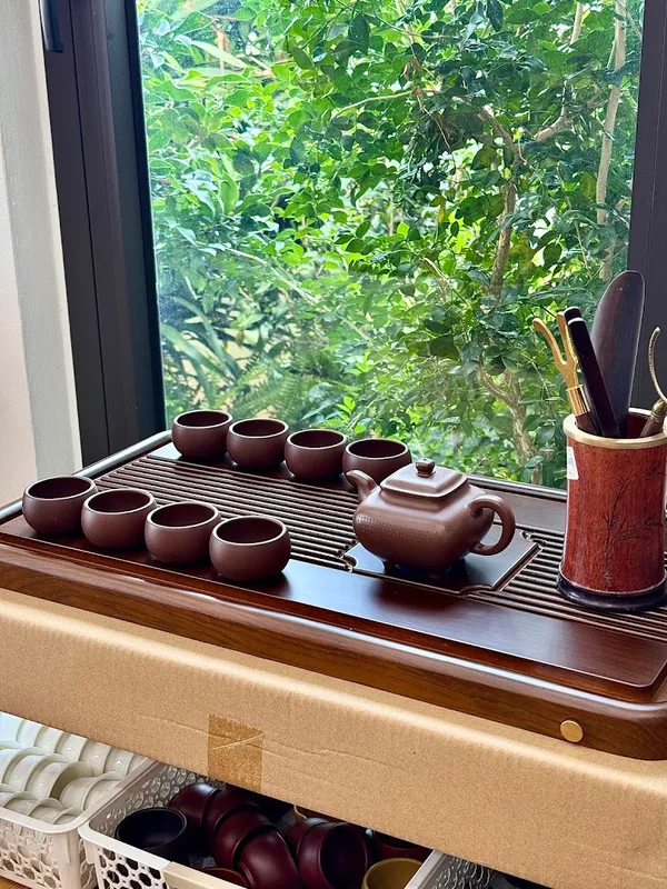 Bộ ấm chén trà bằng gốm được trưng bày trên khay trà.