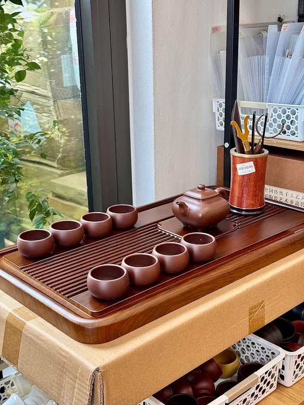 Bộ ấm chén trà bằng gốm được trưng bày trên khay trà.