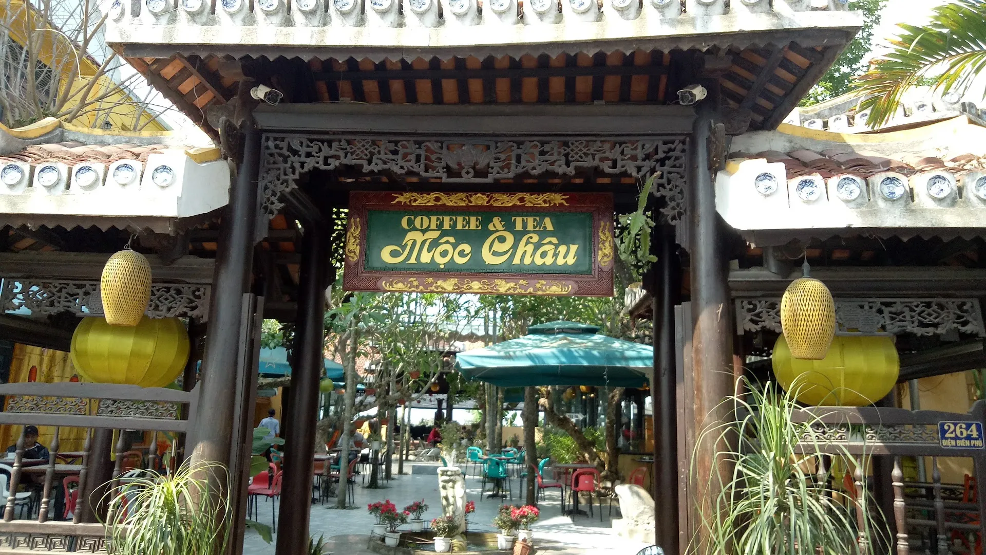 Mặt tiền quán cà phê Mộc Châu với cổng gỗ, sân vườn và khu vực bàn ghế ngoài trời.