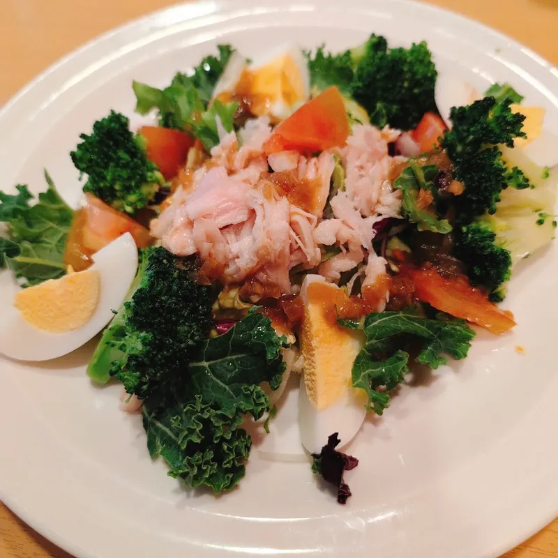 Đĩa salad rau xanh với thịt gà xé, cà chua, bông cải xanh và trứng luộc.