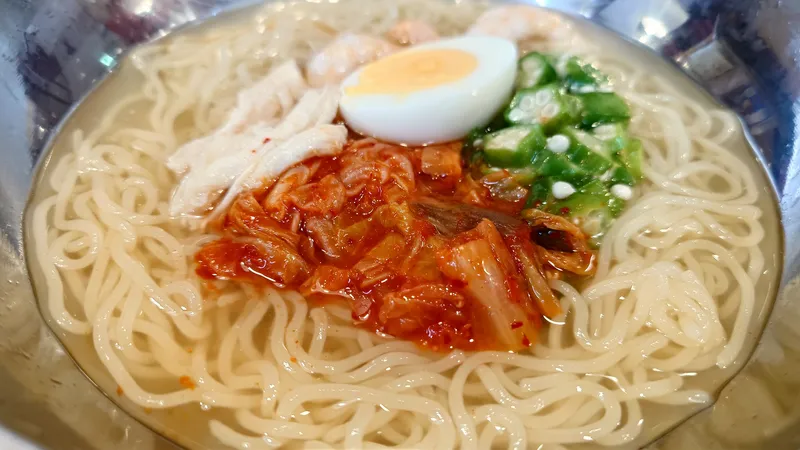 Món mì với thịt gà, kim chi, trứng luộc và rau xanh.