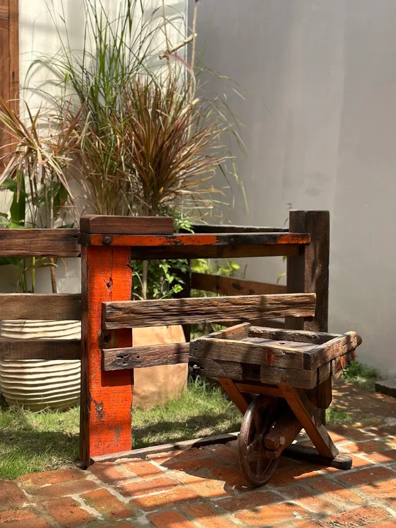 Góc sân lát gạch với xe đẩy gỗ và chậu cây xanh.