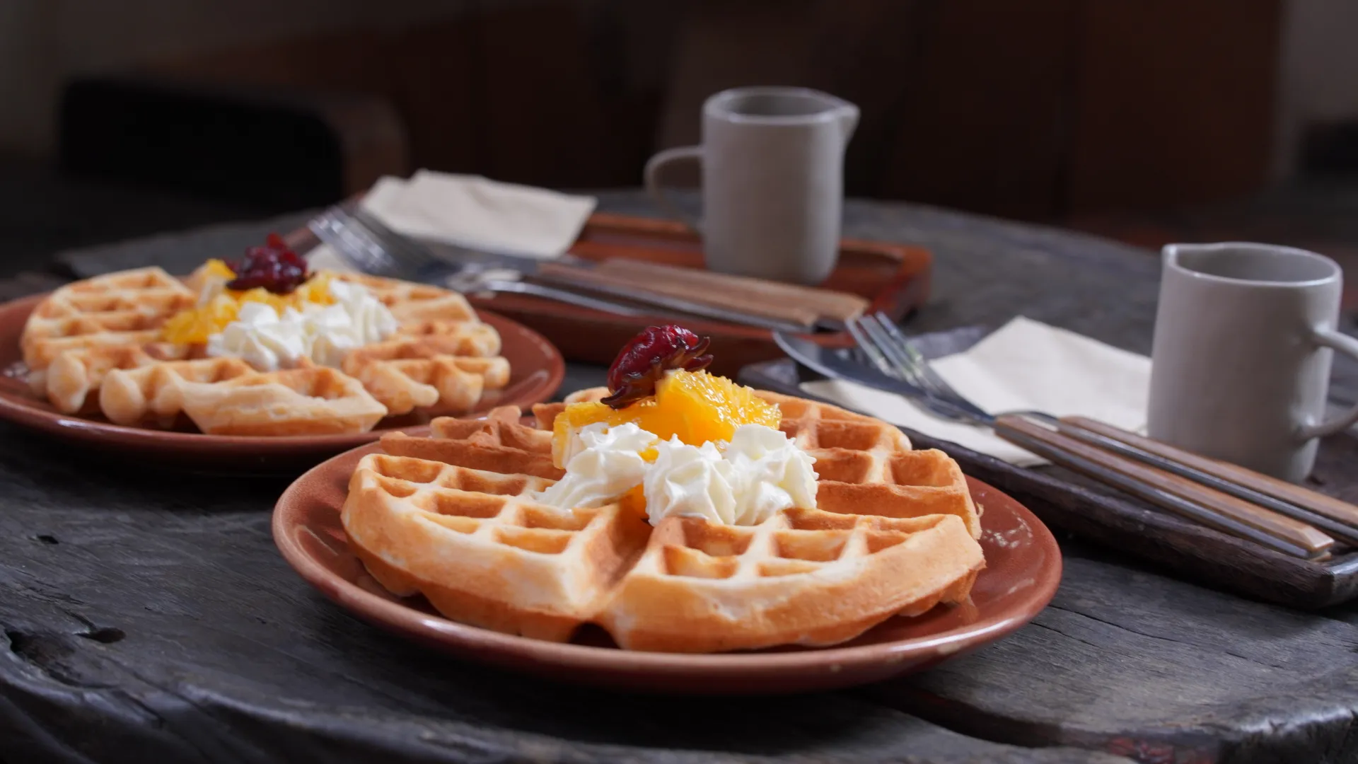 Bánh waffle phủ kem tươi và trái cây, dùng kèm đồ uống nóng.