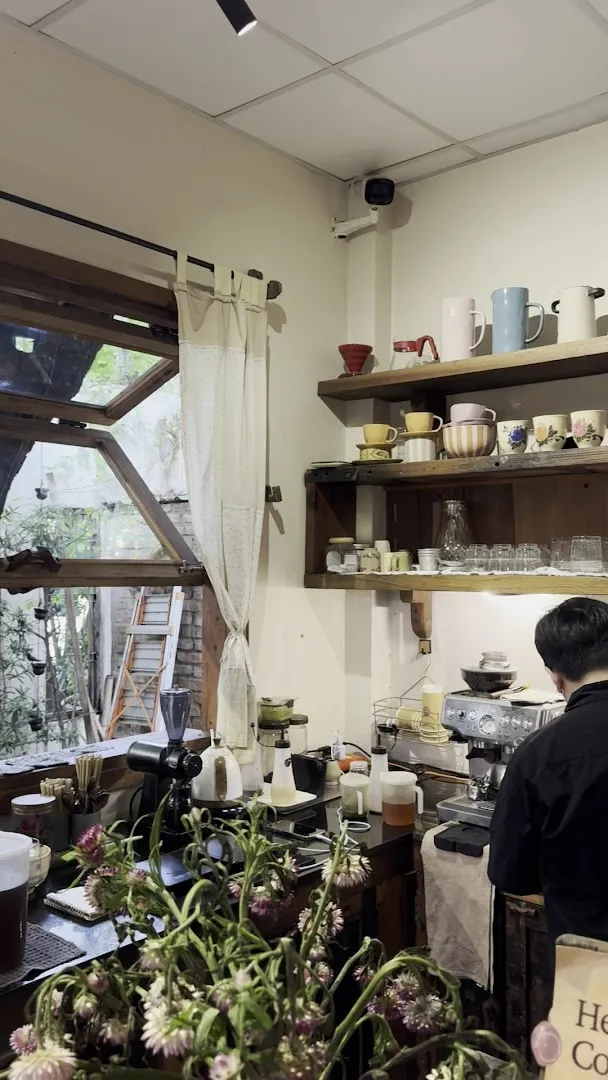 Quầy pha chế với máy espresso, dụng cụ pha cà phê và kệ ly tách.
