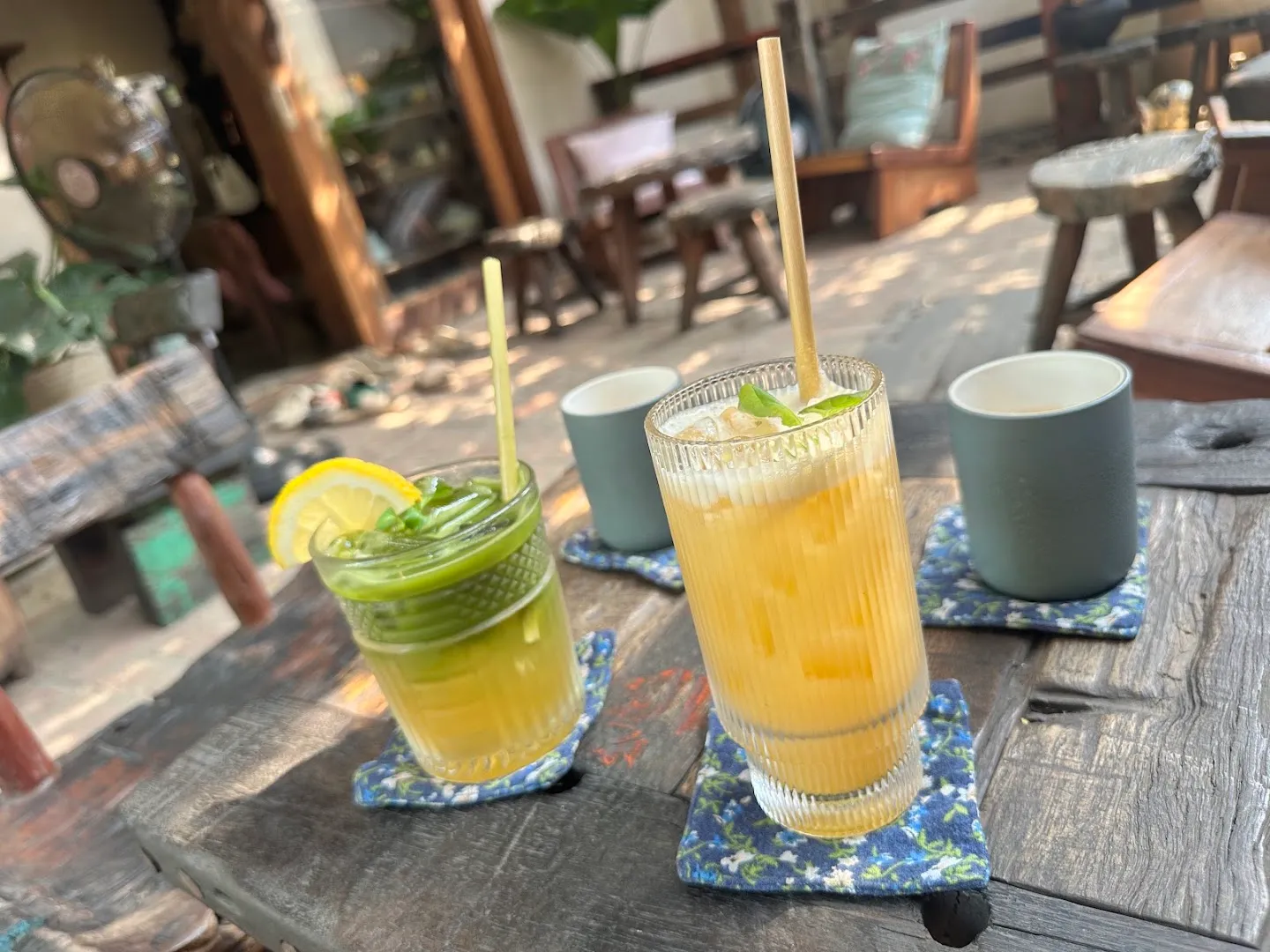 Hai ly đồ uống mát lạnh trên bàn gỗ trong không gian quán cà phê.