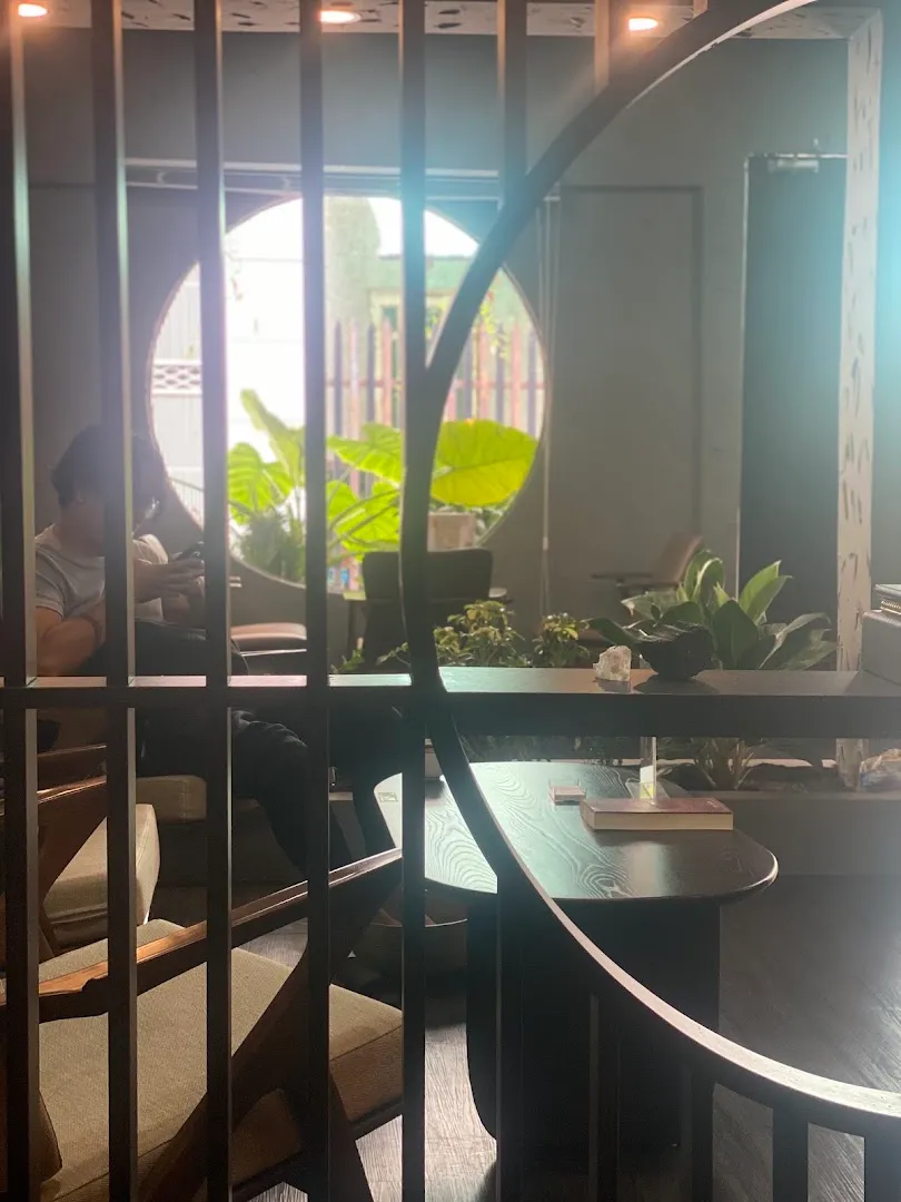 Không gian bên trong với bàn ghế, cây xanh và cửa sổ trang trí hình vòm.