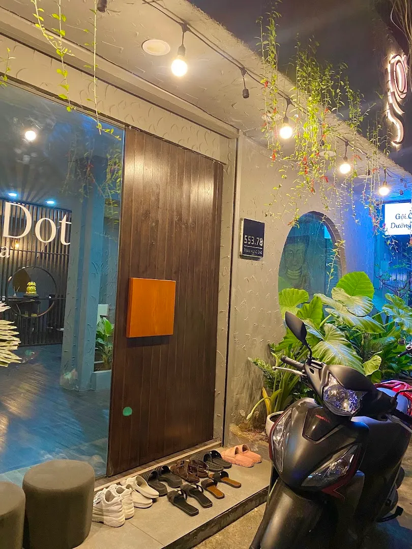 Lối vào không gian spa với cửa gỗ, cây xanh và khu vực để giày dép.