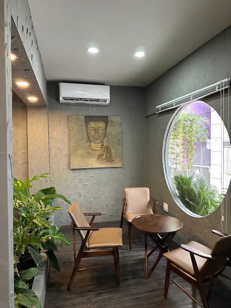 Không gian thư giãn với ghế ngồi, cây xanh và cửa sổ tròn.
