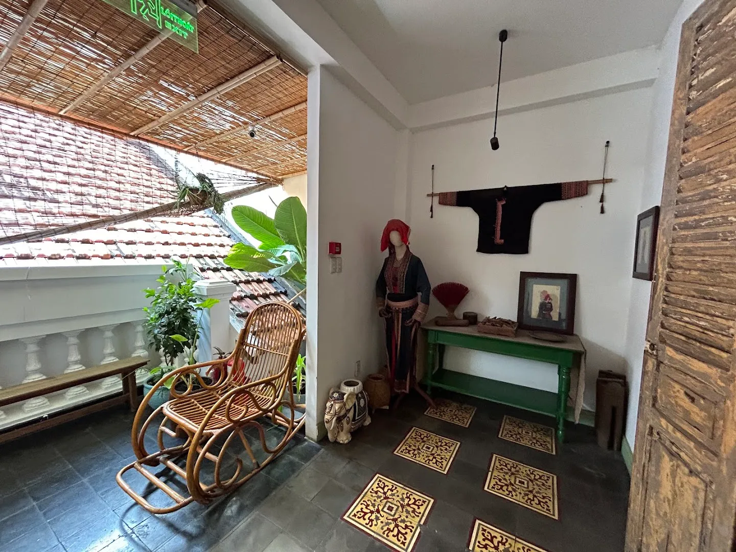 Không gian thư giãn với ghế mây, cây xanh và khu trưng bày trang phục truyền thống.