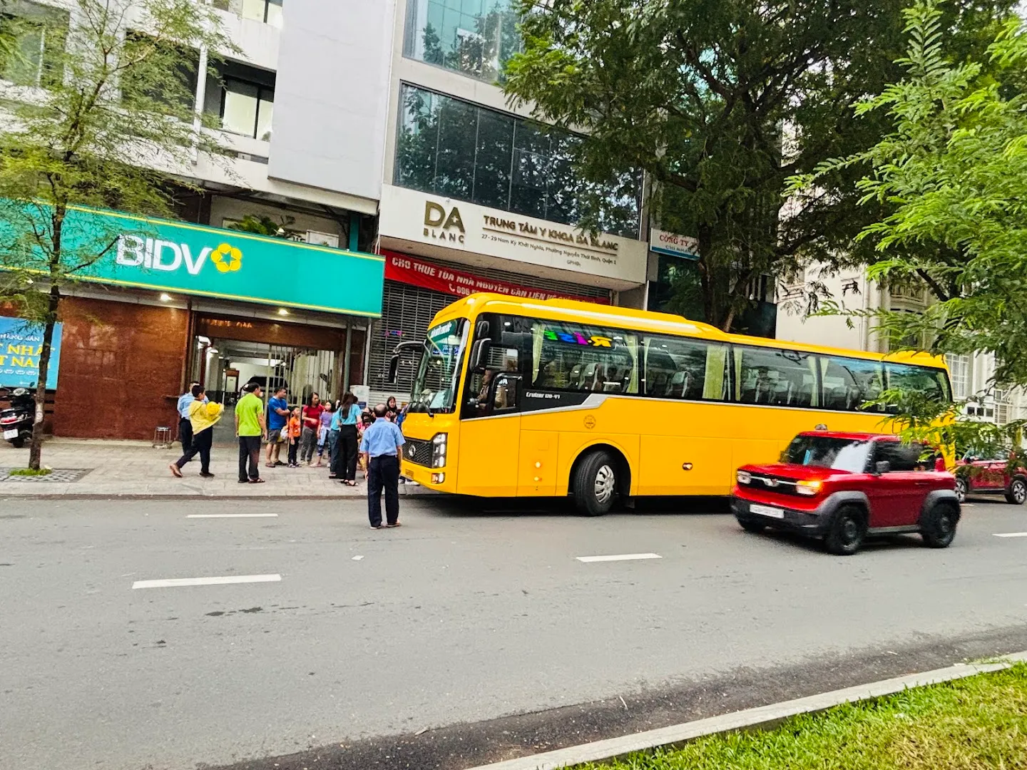 Xe buýt du lịch màu vàng đón đoàn khách trên phố.