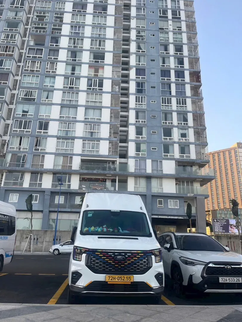 Xe van Ford đậu trước tòa nhà cao tầng.