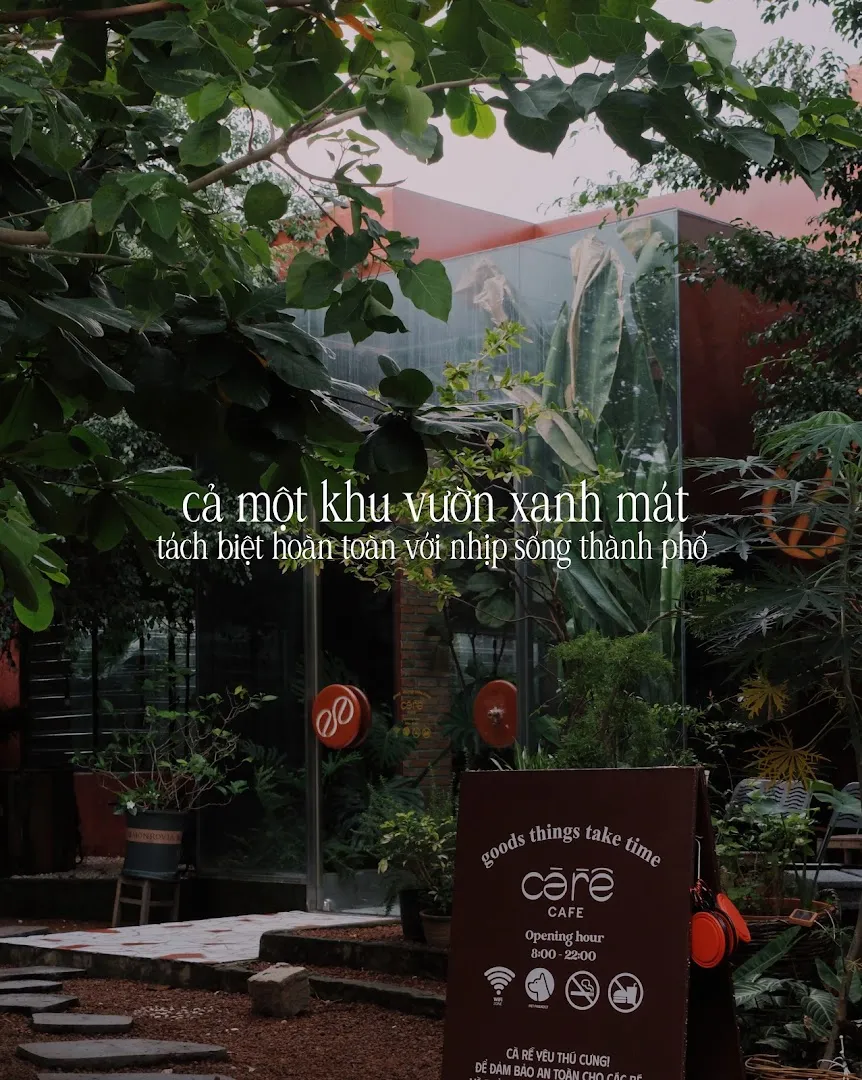 Lối vào Cà Rề Café giữa khu vườn xanh mát, với bảng giờ mở cửa và quy định của quán.