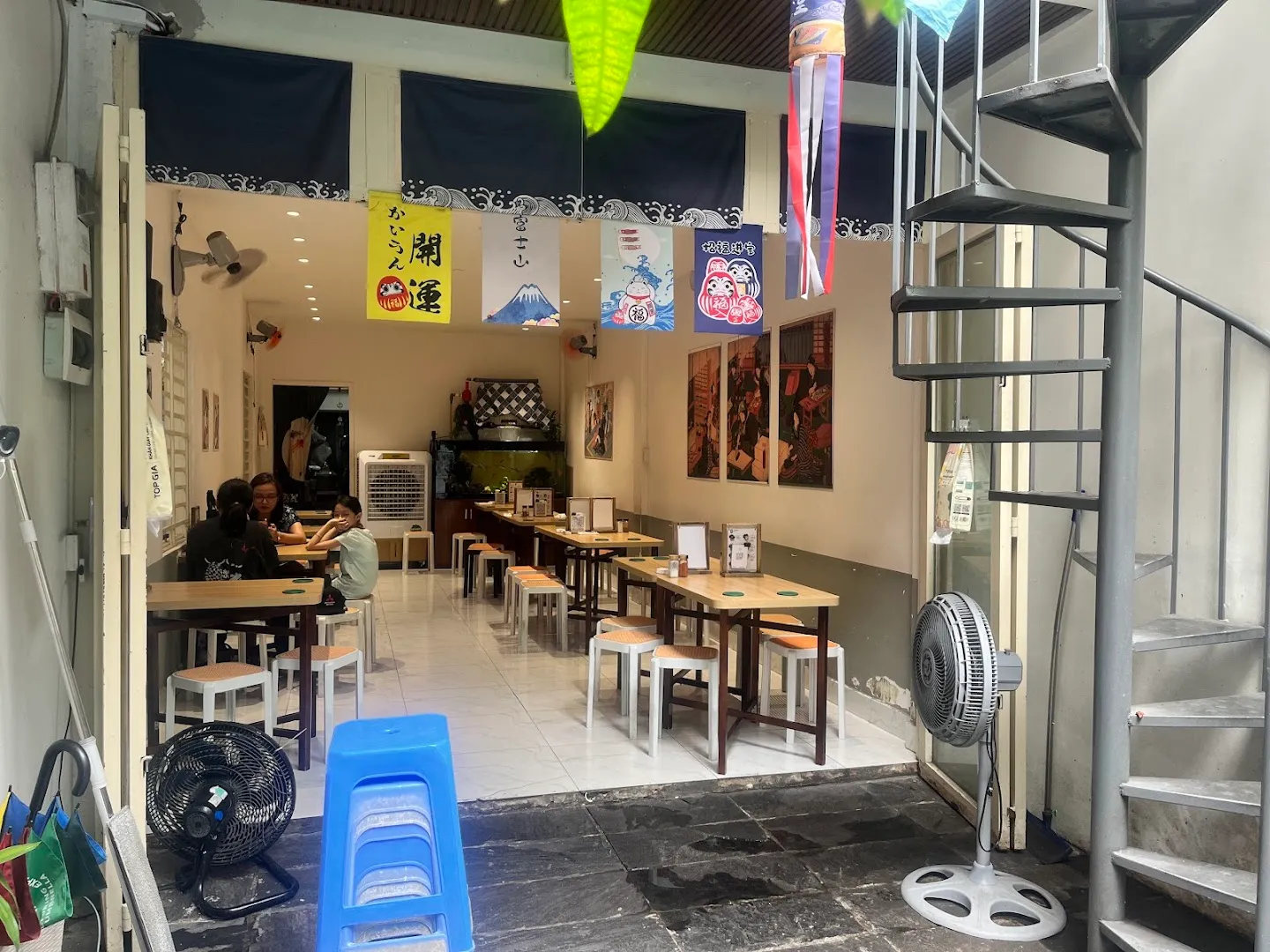 Không gian bên trong nhà hàng với bàn ghế, tranh và trang trí phong cách Nhật Bản.