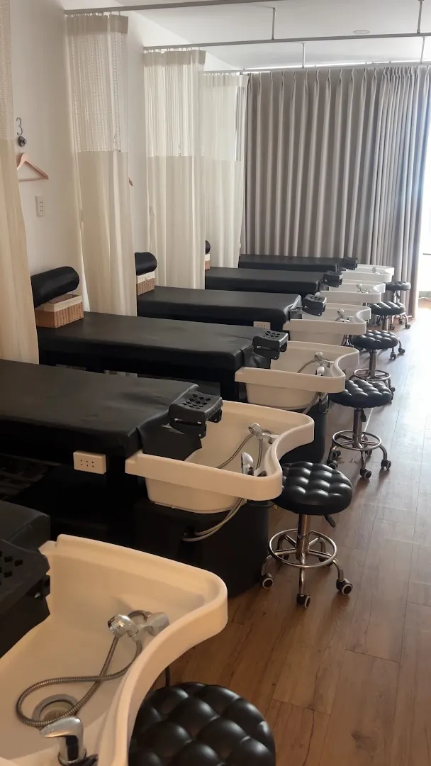 Không gian spa với các giường chăm sóc và bồn rửa chân được bố trí riêng tư bằng rèm.