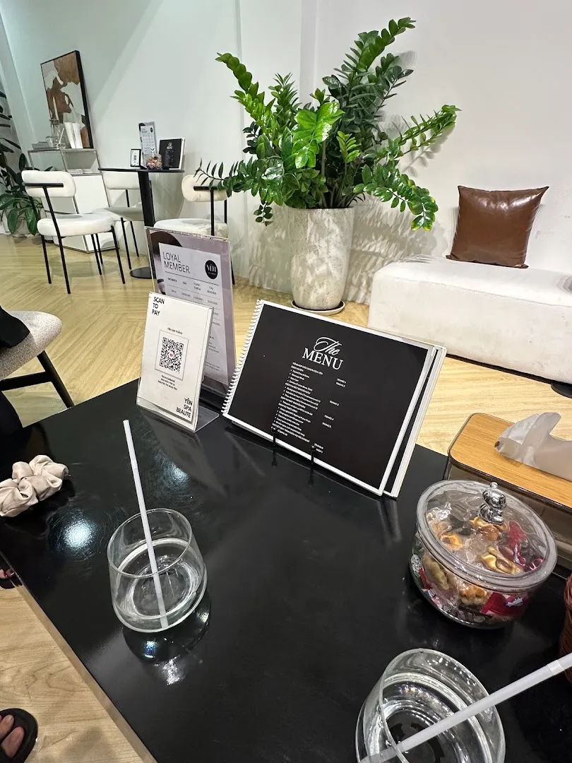 Không gian tiếp khách với bàn menu, ghế ngồi và cây xanh.