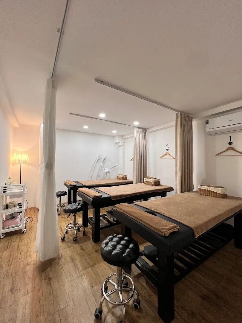 Phòng trị liệu với các giường massage, rèm ngăn riêng và thiết bị chăm sóc da.