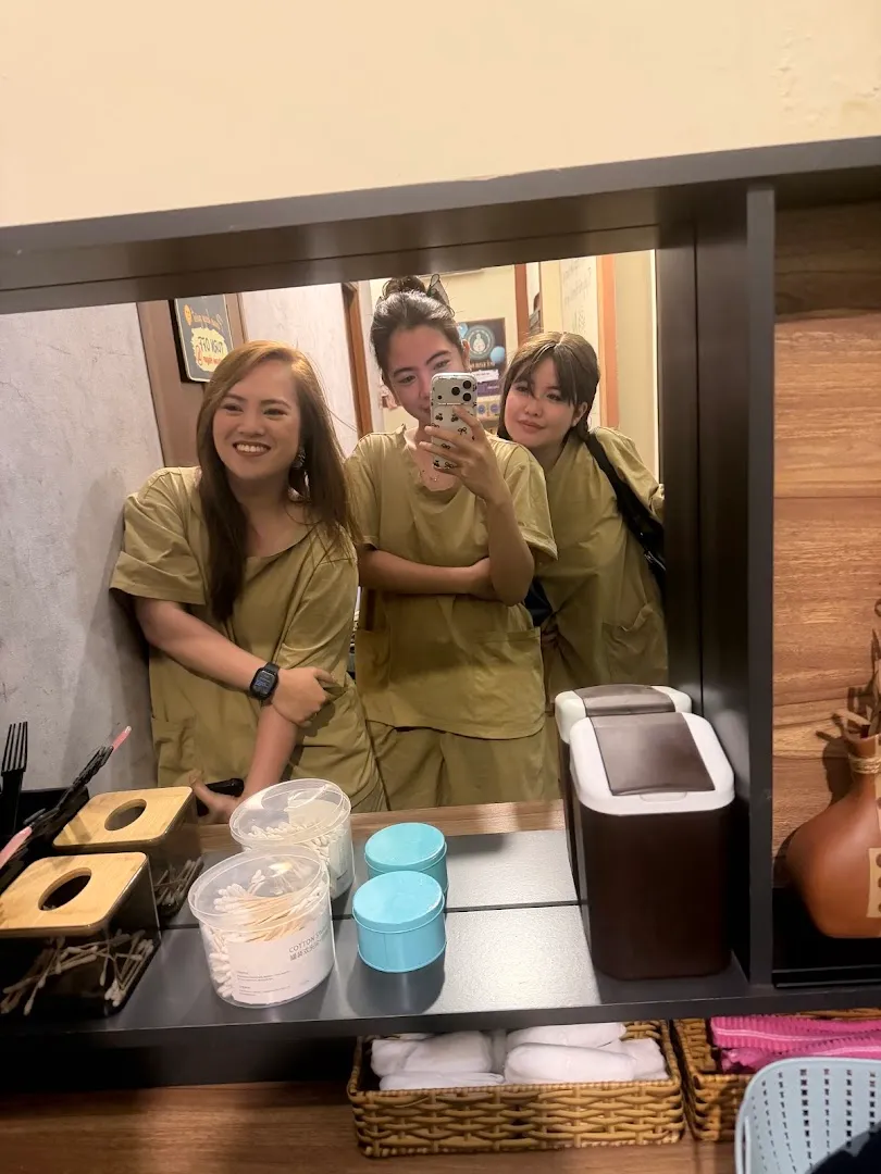 Ba người mặc đồng phục đứng trước gương trong không gian spa, cạnh các vật dụng chăm sóc khách hàng.