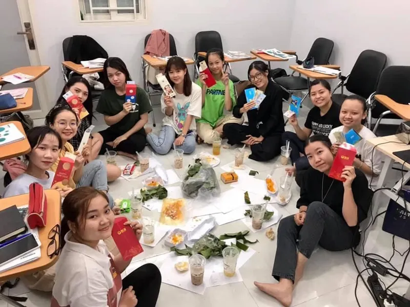 Nhóm người trong phòng học, cùng cầm tài liệu và sách học tập.