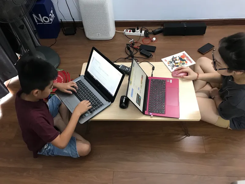 Hai người cùng học tập và làm việc trên máy tính tại bàn.