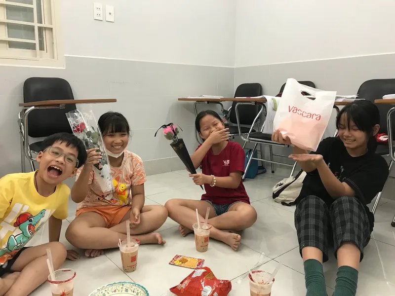 Nhóm người trẻ vui vẻ trong một phòng học có bàn ghế xếp thành lớp.