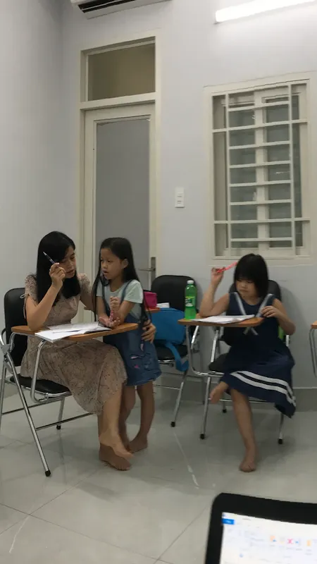 Không gian lớp học với bàn ghế học viên và hoạt động học tập.