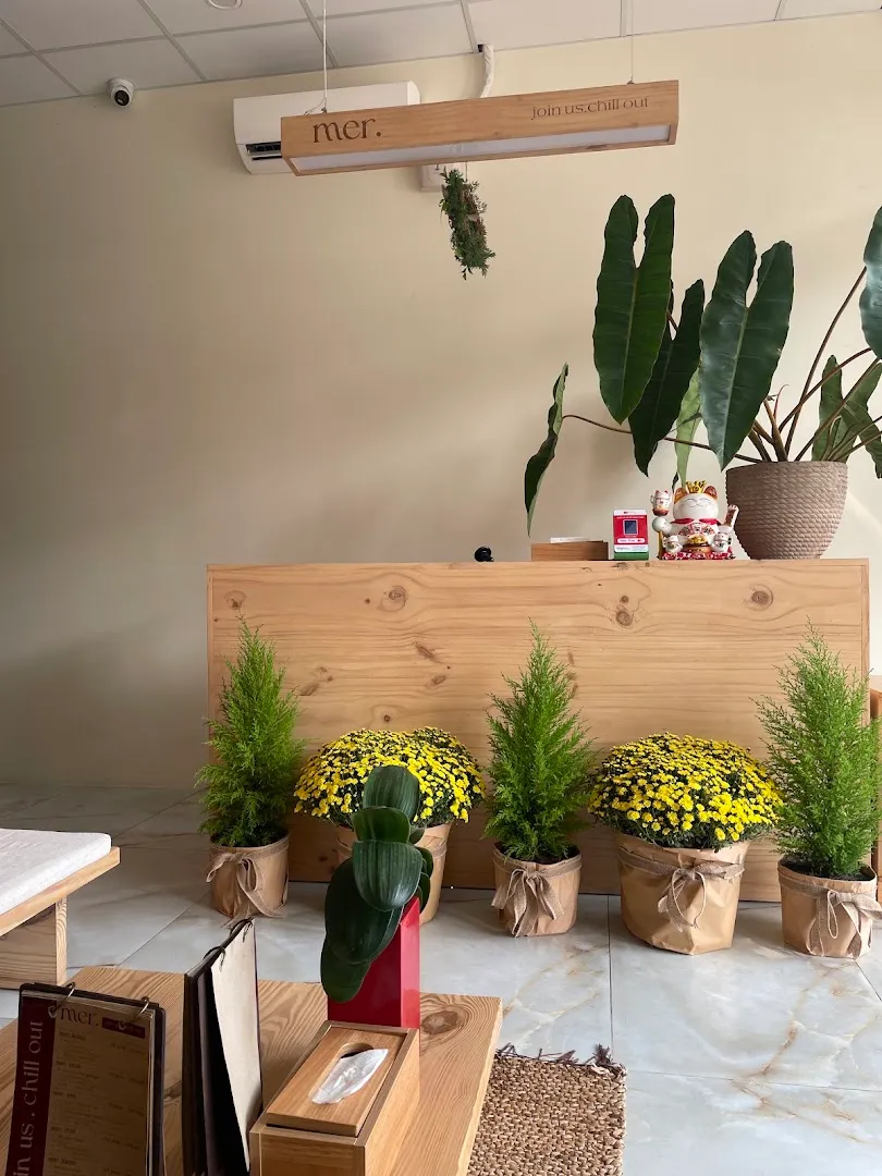 Quầy lễ tân bằng gỗ với cây xanh và hoa trang trí trong không gian spa.