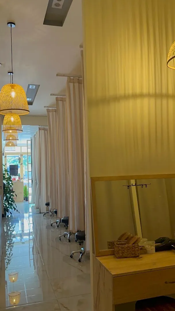 Không gian spa với các khu vực chăm sóc riêng được ngăn bằng rèm và ánh đèn ấm áp.