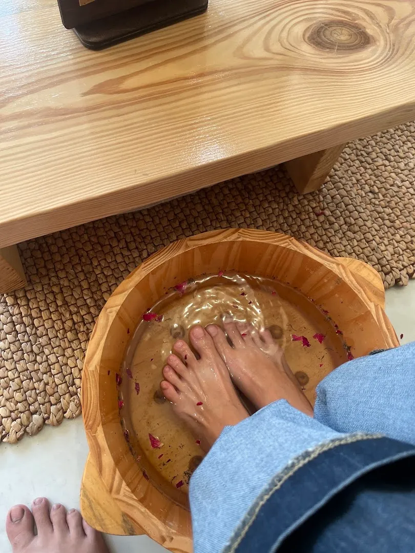 Ngâm chân thư giãn trong chậu gỗ với nước và cánh hoa.
