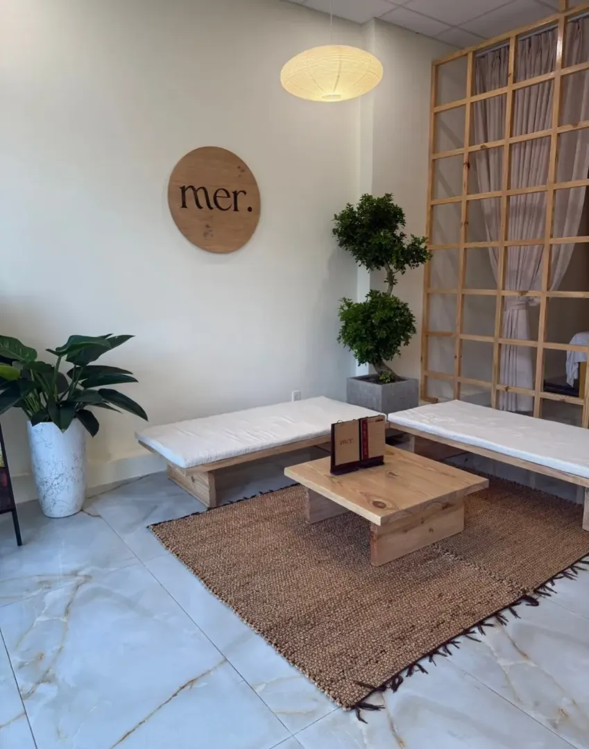 Không gian thư giãn với giường spa, bàn trà và cây xanh.