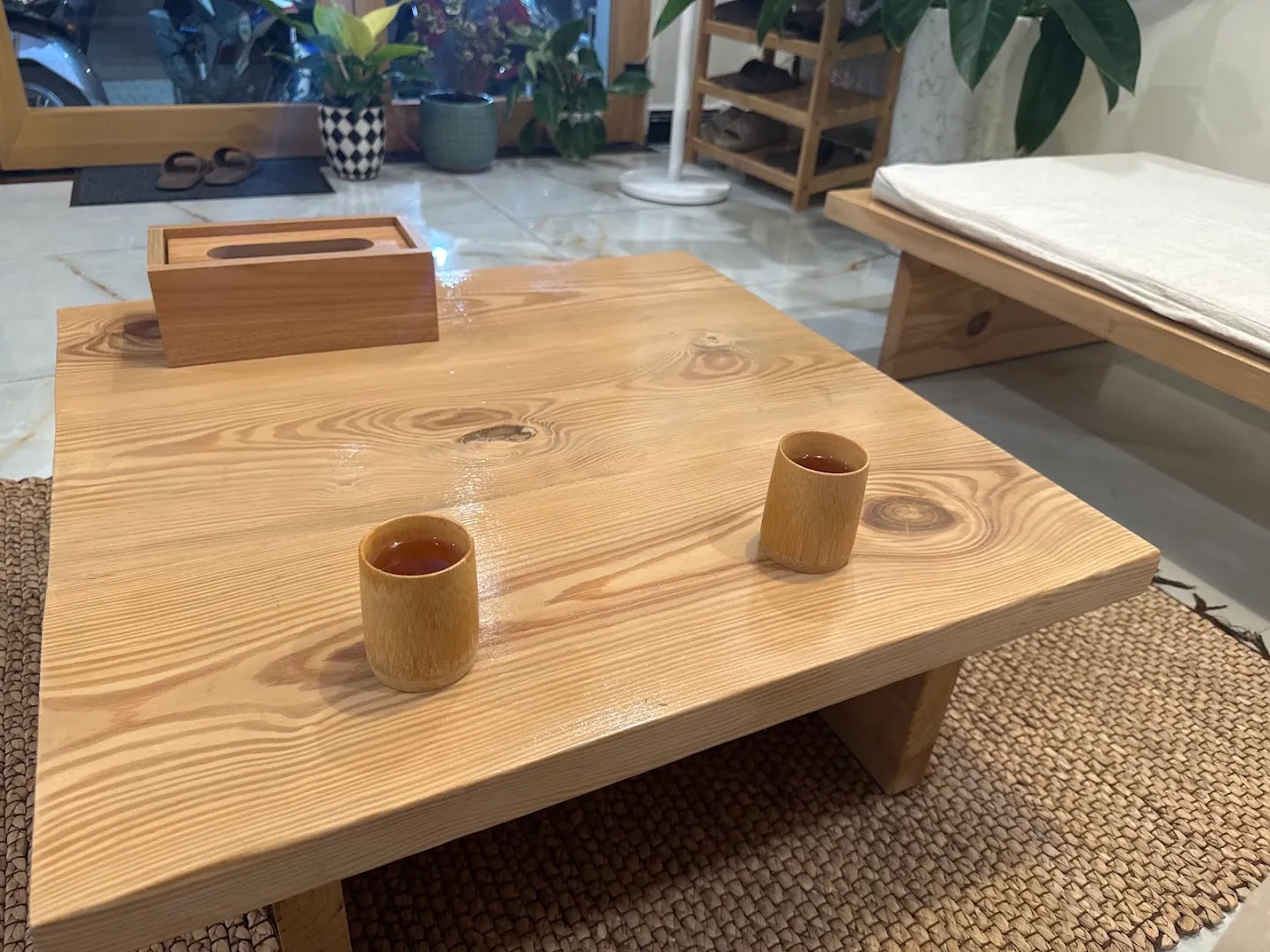 Không gian thư giãn với bàn trà gỗ, ghế đệm và cây xanh.