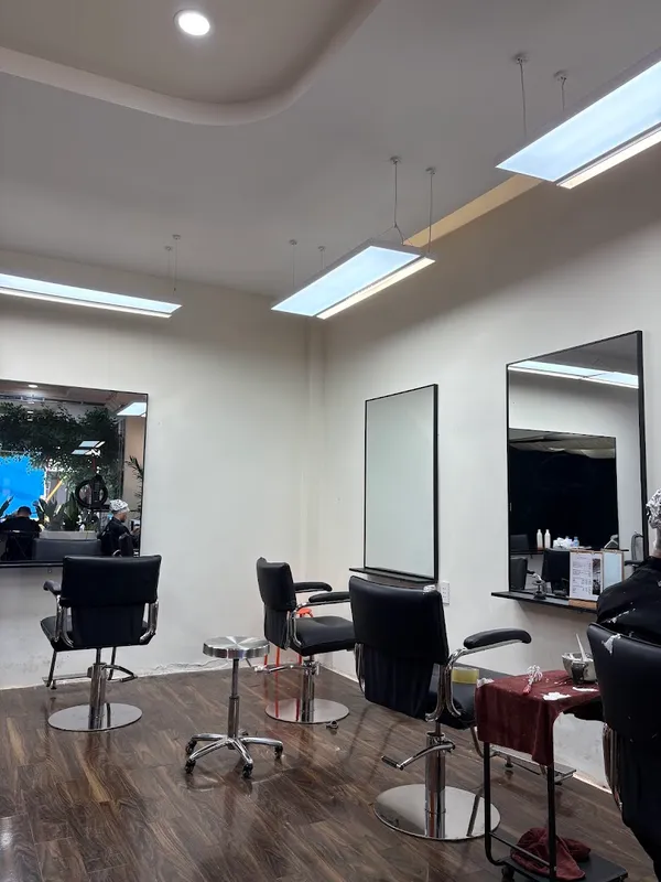 Không gian salon tóc với các ghế làm tóc, gương lớn và khu vực tạo kiểu.