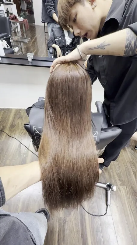 Thợ làm tóc đang chăm sóc mái tóc dài tại salon.