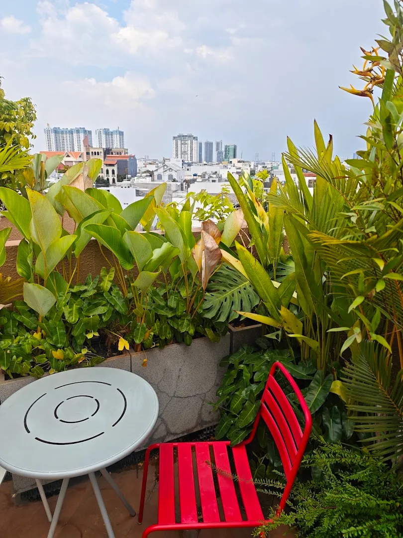Góc ngồi ngoài trời giữa khu vườn xanh, nhìn ra khung cảnh thành phố.
