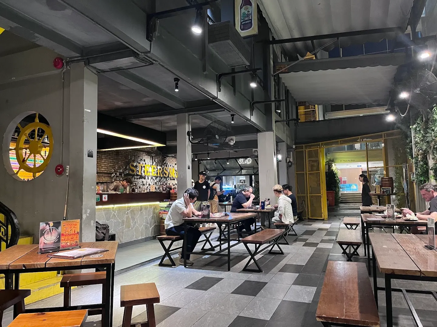 Không gian quán với bàn ghế gỗ, quầy bar và khu vực phục vụ rộng rãi.
