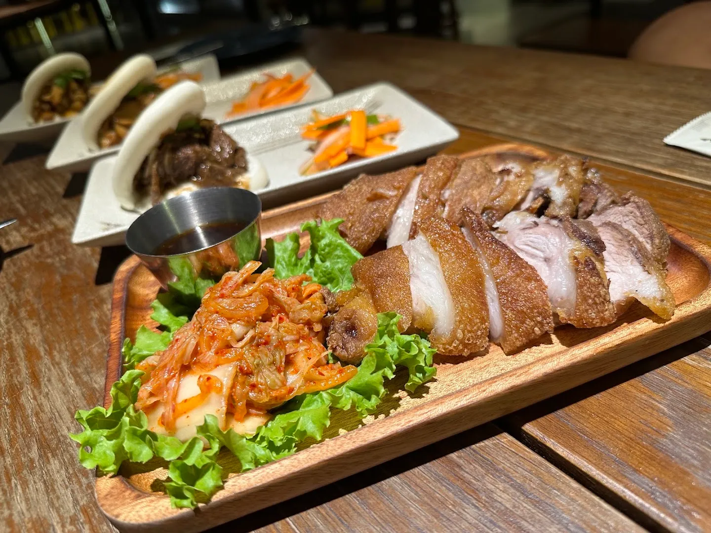 Đĩa thịt quay thái lát ăn kèm kim chi, rau xà lách và nước chấm.