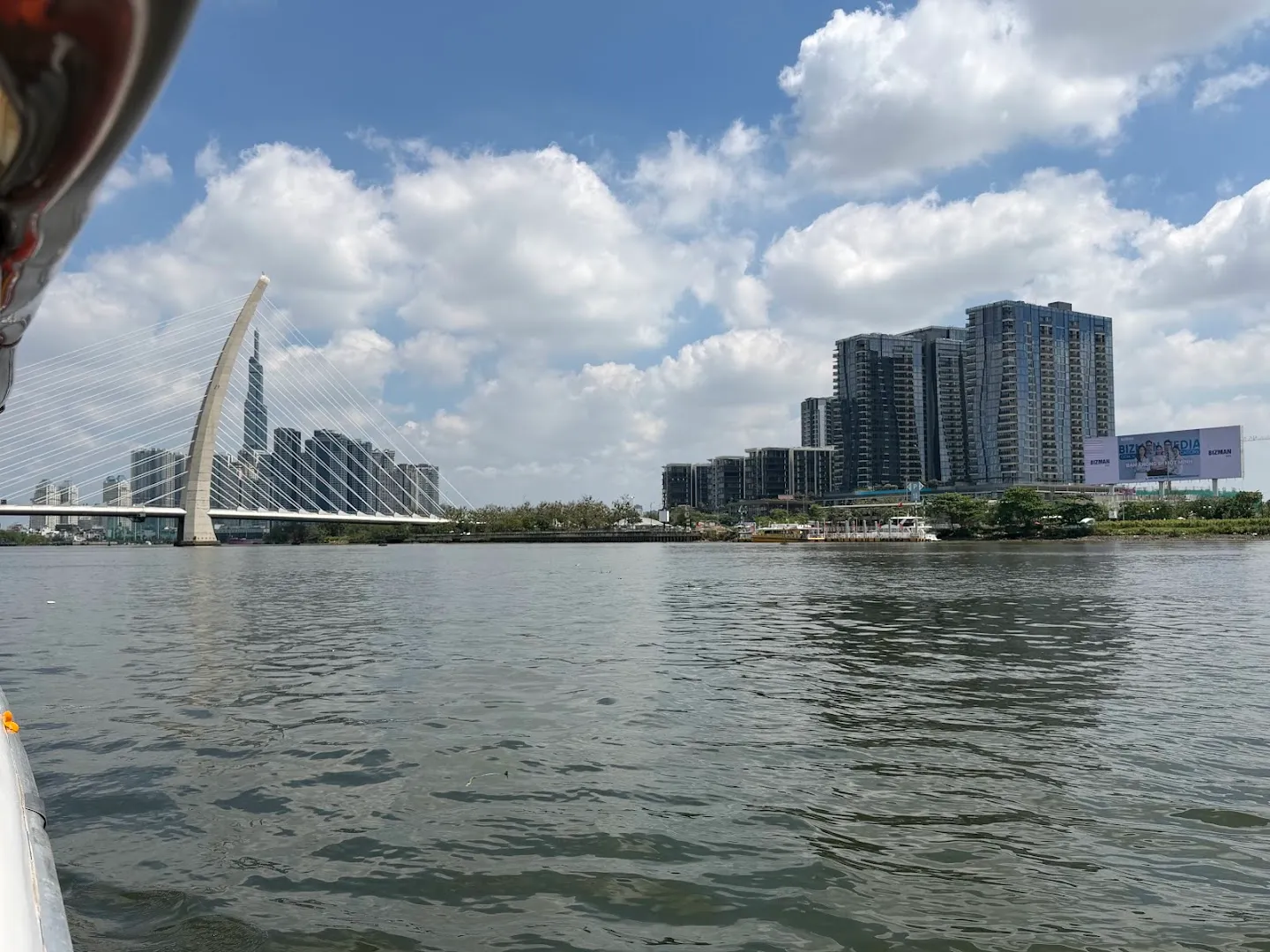 Góc nhìn từ trên thuyền ra cây cầu dây văng và đường chân trời ven sông.
