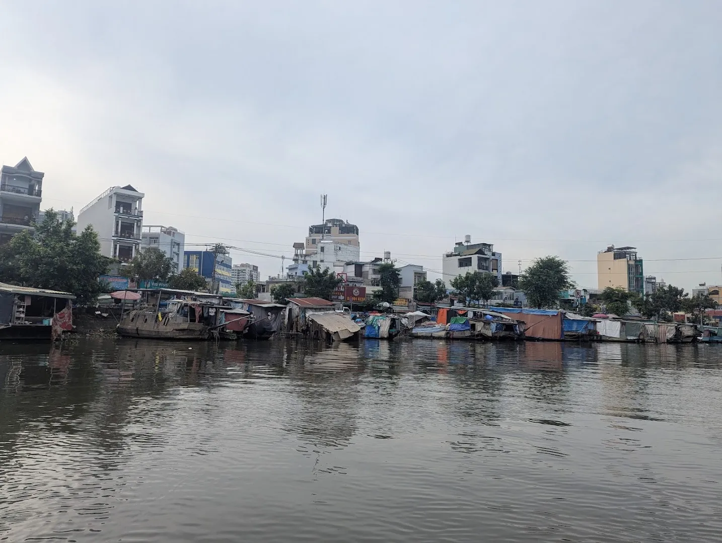 Khung cảnh khu dân cư ven sông với các thuyền neo đậu bên bờ.