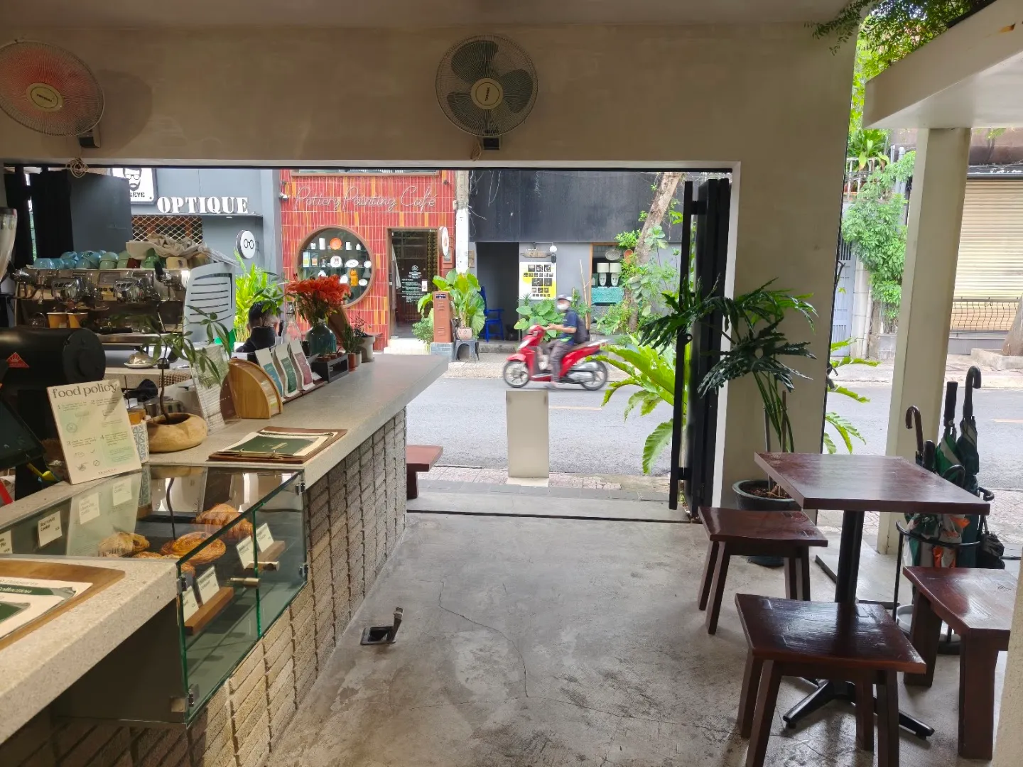 Không gian bên trong quán với quầy pha chế, tủ bánh và khu vực ngồi gần cửa.